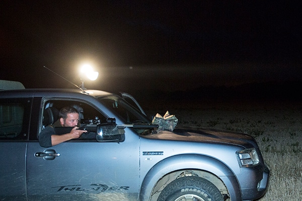 A night shooter in their vehicle aiming down the sights of their rifle