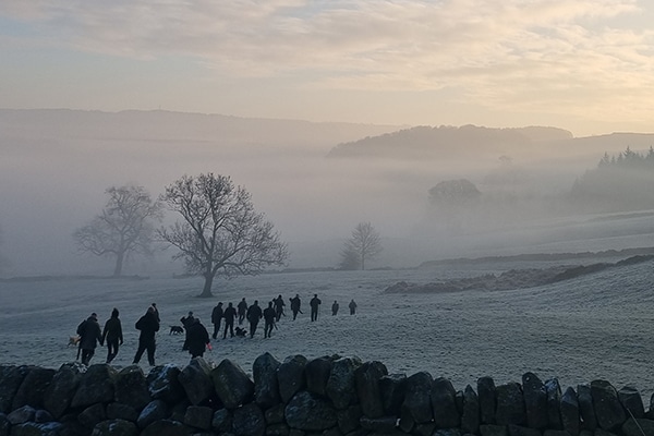 A group of shooters walking through a field in the winter