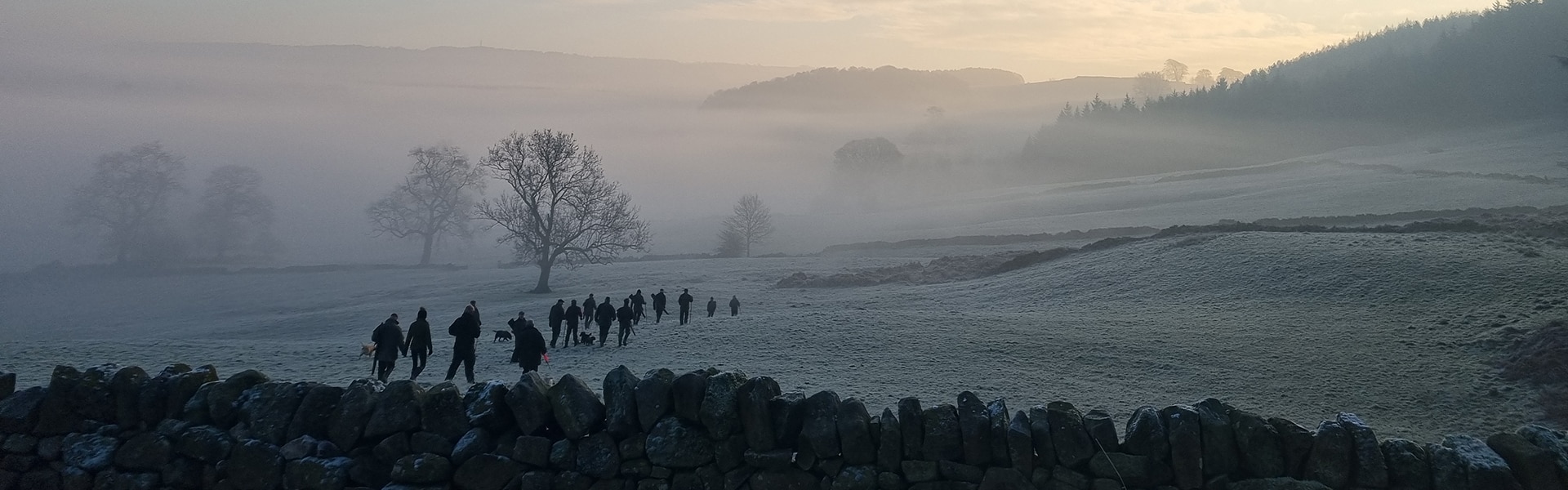 A group of shooters walking through a field in the winter