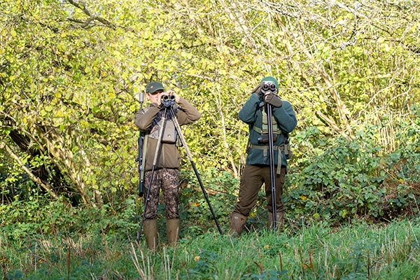 A pair of deer stalkers watching through binoculars