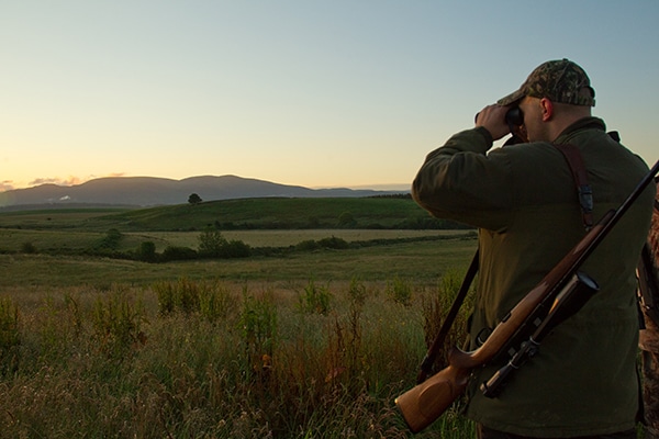 A deer stalker looking through their binoculars
