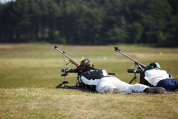 Two target shooters lying down aiming down the scopes of their rifles