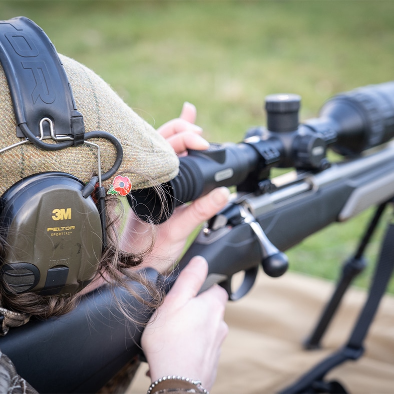 A target shooter aiming down the scope of their rifle