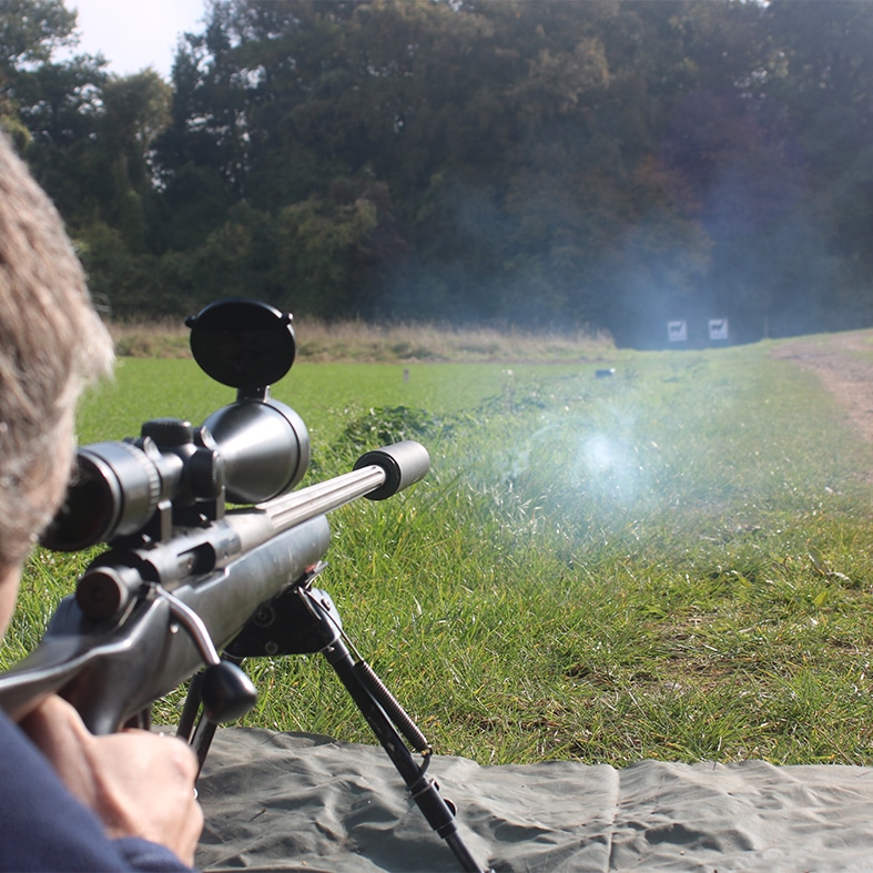 A target shooter aiming down a scope at a target