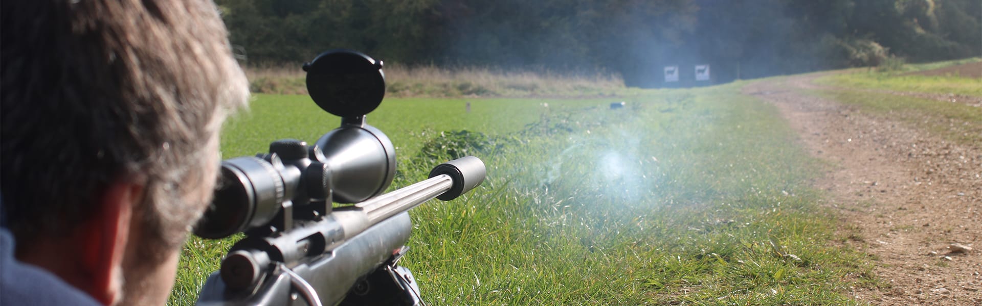 A target shooter aiming down a scope at a target