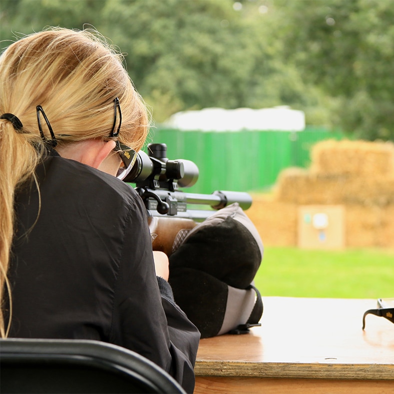 Air rifle shooter aiming down her scope