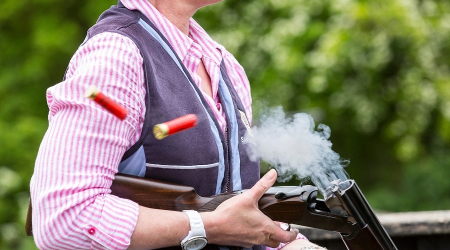 Women shooter holding a shotgun whilst shells eject from it