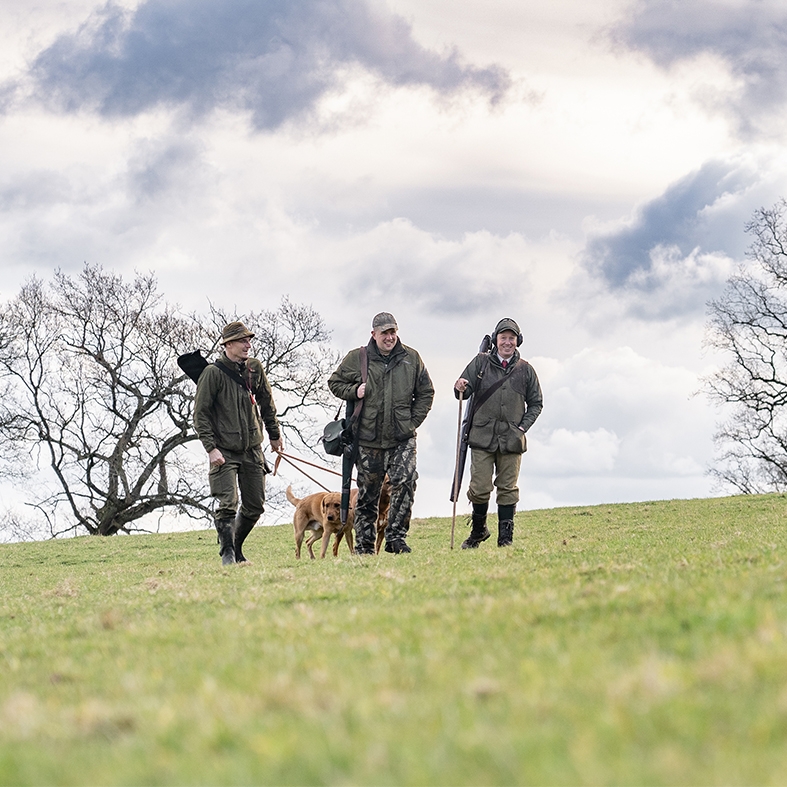 Game shooters walking in a field