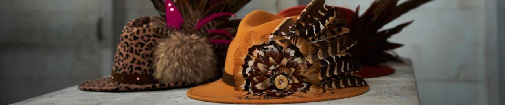 Three hats on a surface with feathers attached to them