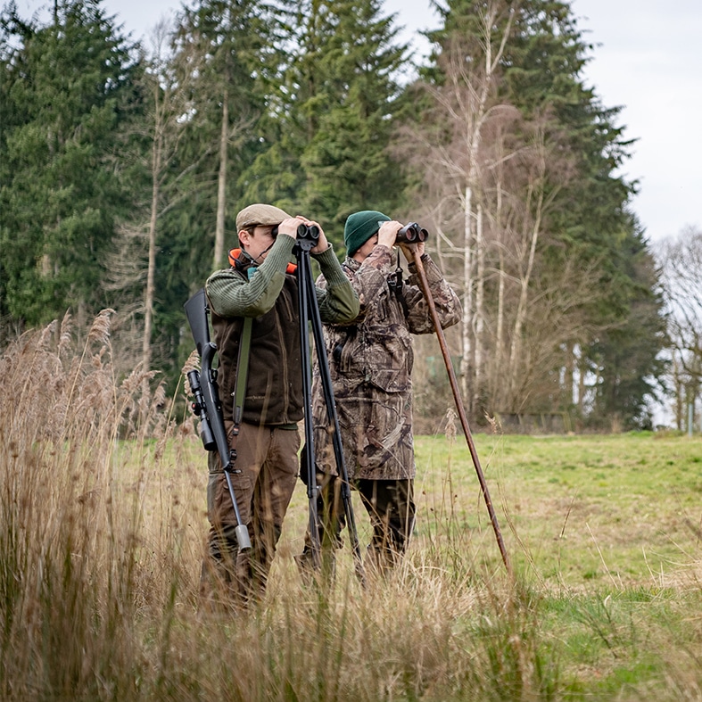 Two deer stalkers looking through binoculars