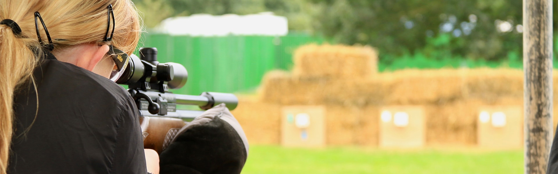 A young shot aiming an air rifle down a range
