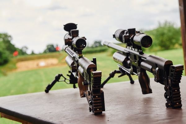 Two air rifles pointing out onto a target range