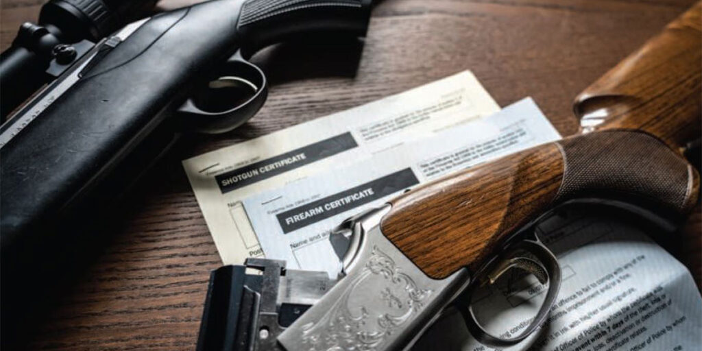 Two shotguns on a table with firearms certificates underneath them