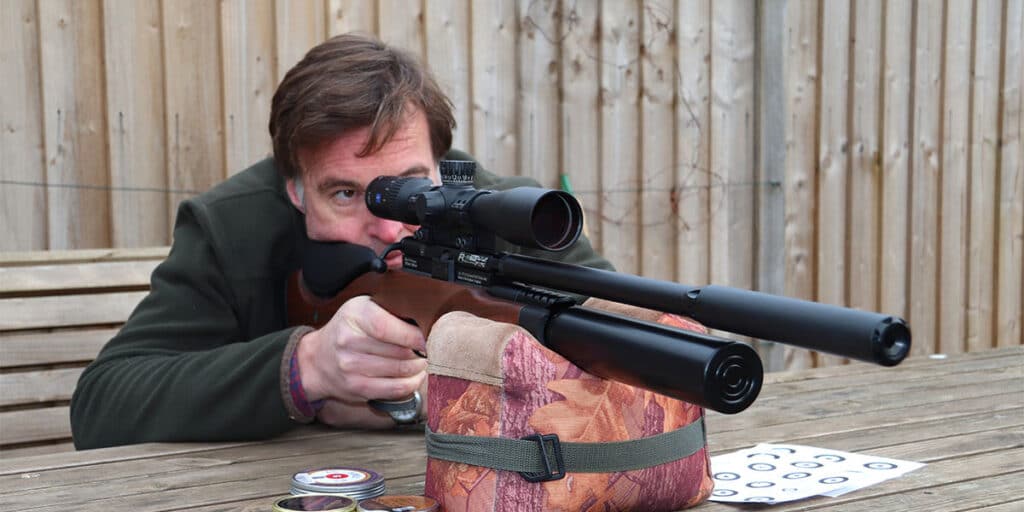 Air rifle shooter aiming down a scope