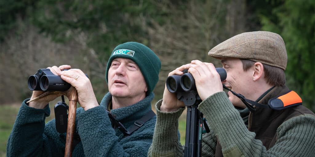 Deer stalkers looking through binoculars