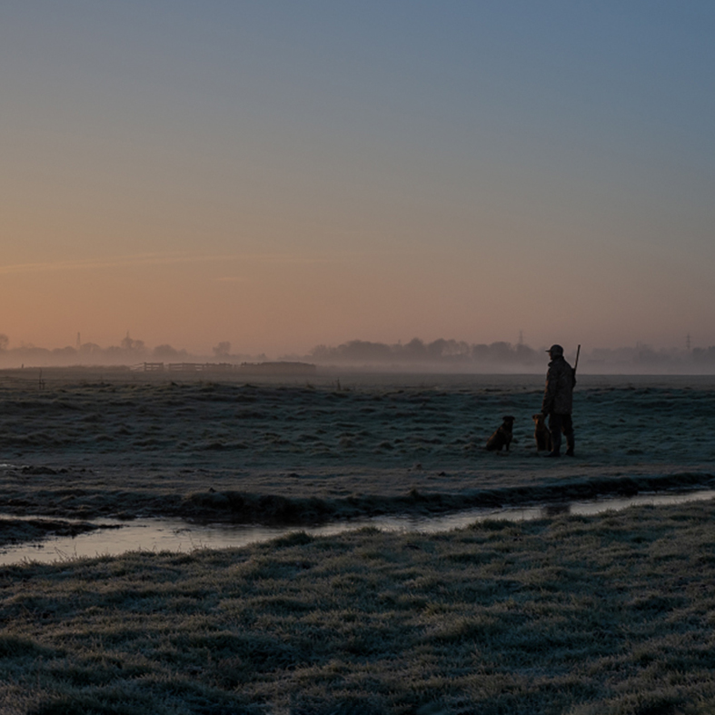 A wildfowler standing with their gundog