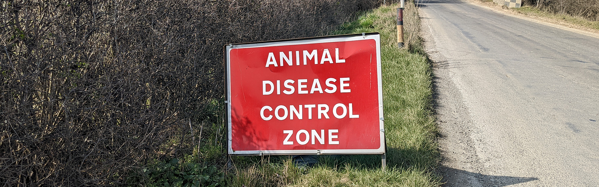 An animal disease control sign on the side of a country road