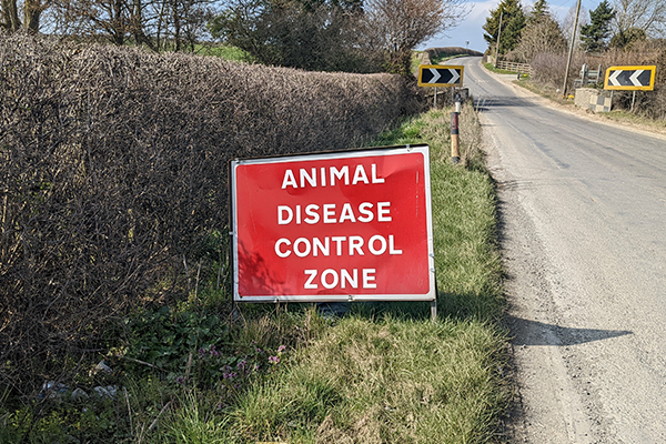 An animal disease control sign on the side of a country road