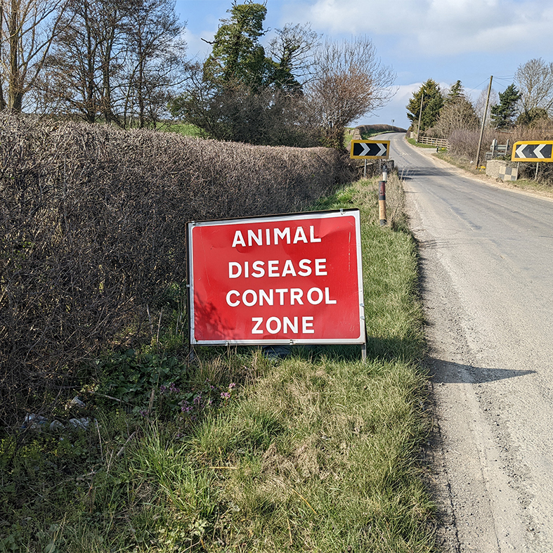 An animal disease control sign on the side of a country road