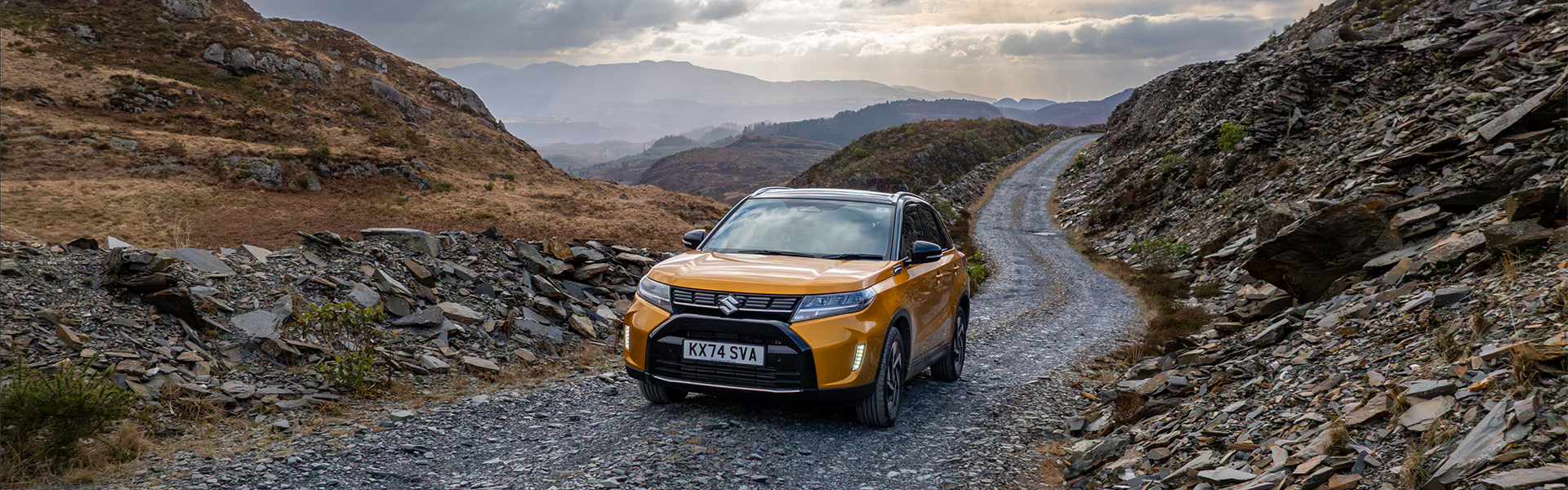 Suzuki car driving along a stone road